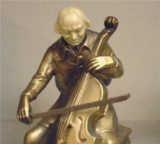   metal standing on a base of white polished onyx; the cellists heads